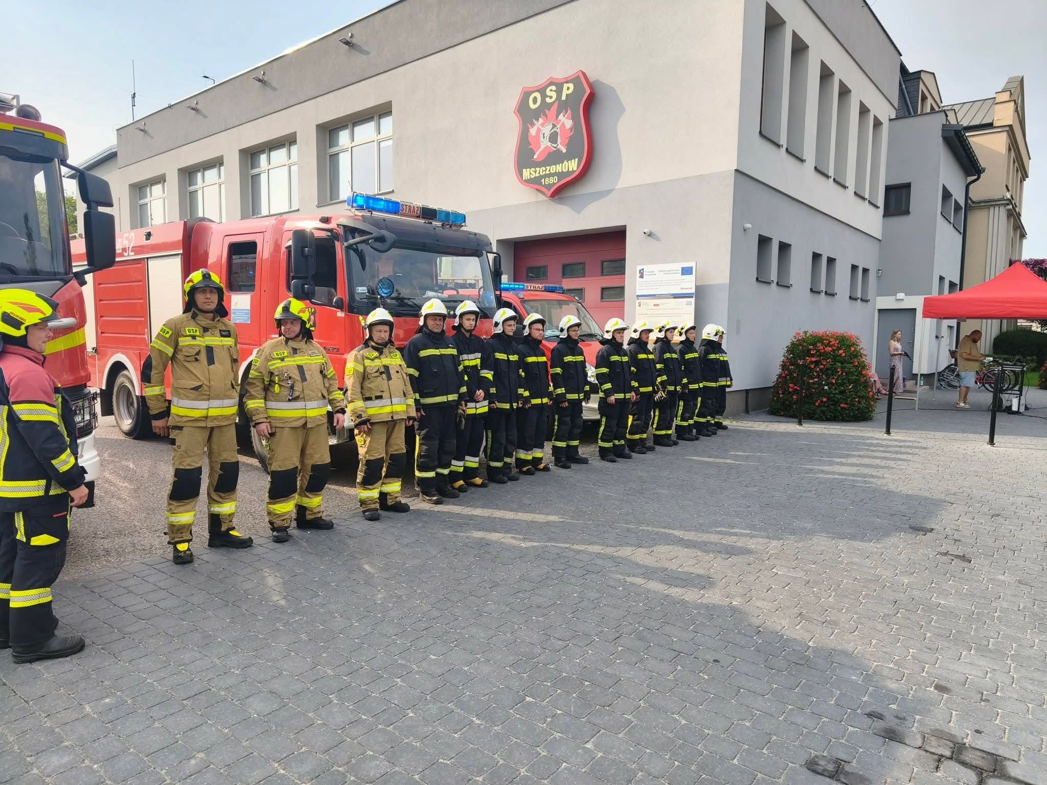Strażacy stojący w szeregu przed strażnicą OSP Mszczonów podczas Godziny W